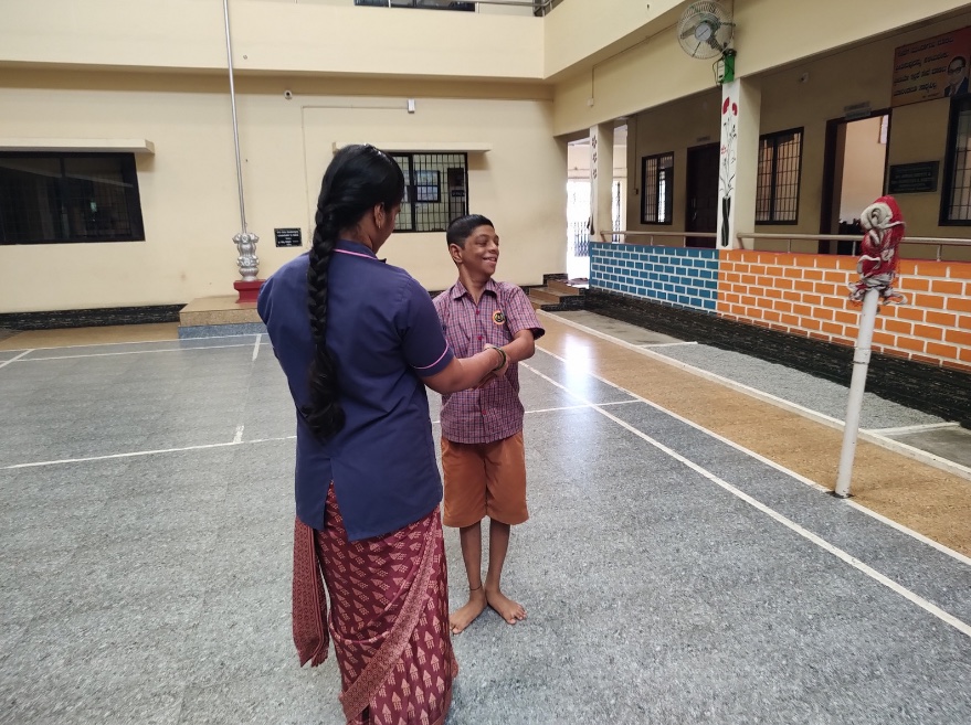A staff member greeting a student in the courtyard at Chethana Special School